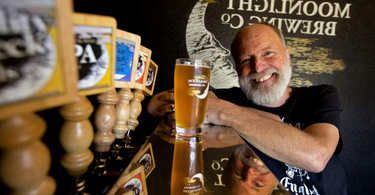Moonlight Brewing founder Brian Hunt with glass of beer beside tap handles