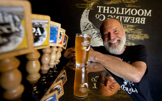 Moonlight Brewing founder Brian Hunt with glass of beer beside tap handles